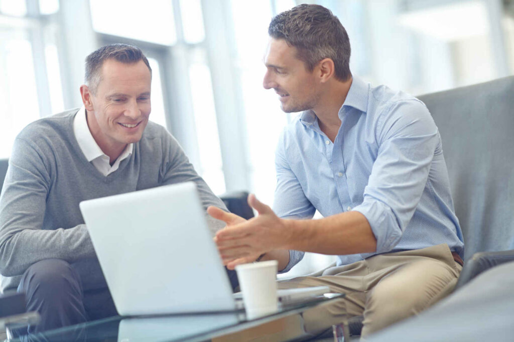 Zwei Männer vor einem Notebook, die etwas besprechen